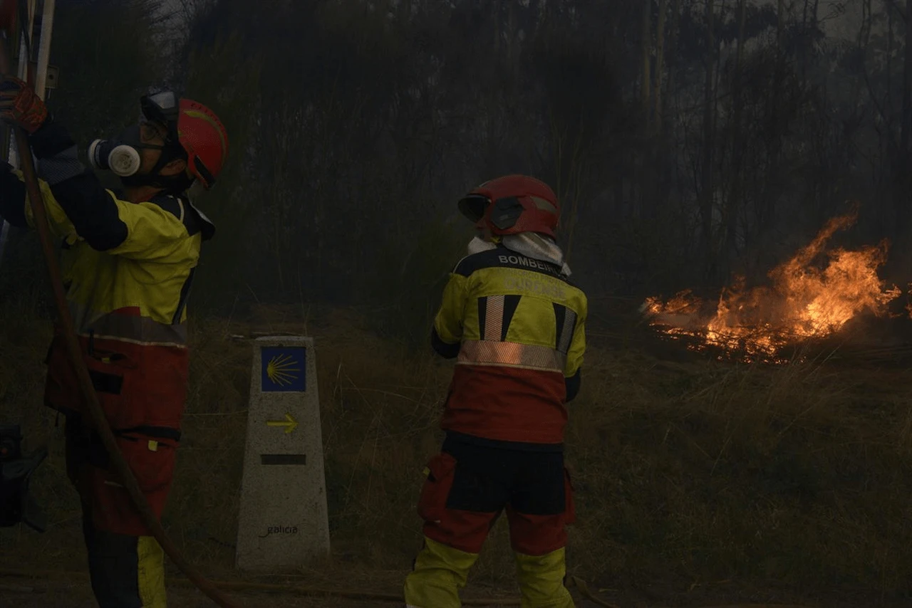 Dos bomberos durante las labores de extinción de un incendio forestal, la carretera nacional 525, a 15 de agosto de 2026, en O Riós, Ourense, Galicia (España) / Foto: EP Dos bomberos durante las labores de extinción de un incendio forestal, la carretera nacional 525, a 15 de agosto de 2026, en O Riós, Ourense, Galicia (España) / Foto: EP