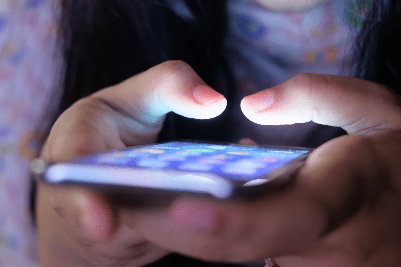 Primer plano de las manos de una persona usando un teléfono móvil con la pantalla iluminada el uso adictivo de móviles y redes se asocia a peor salud mental y sueño en los jóvenes / Foto: PX
