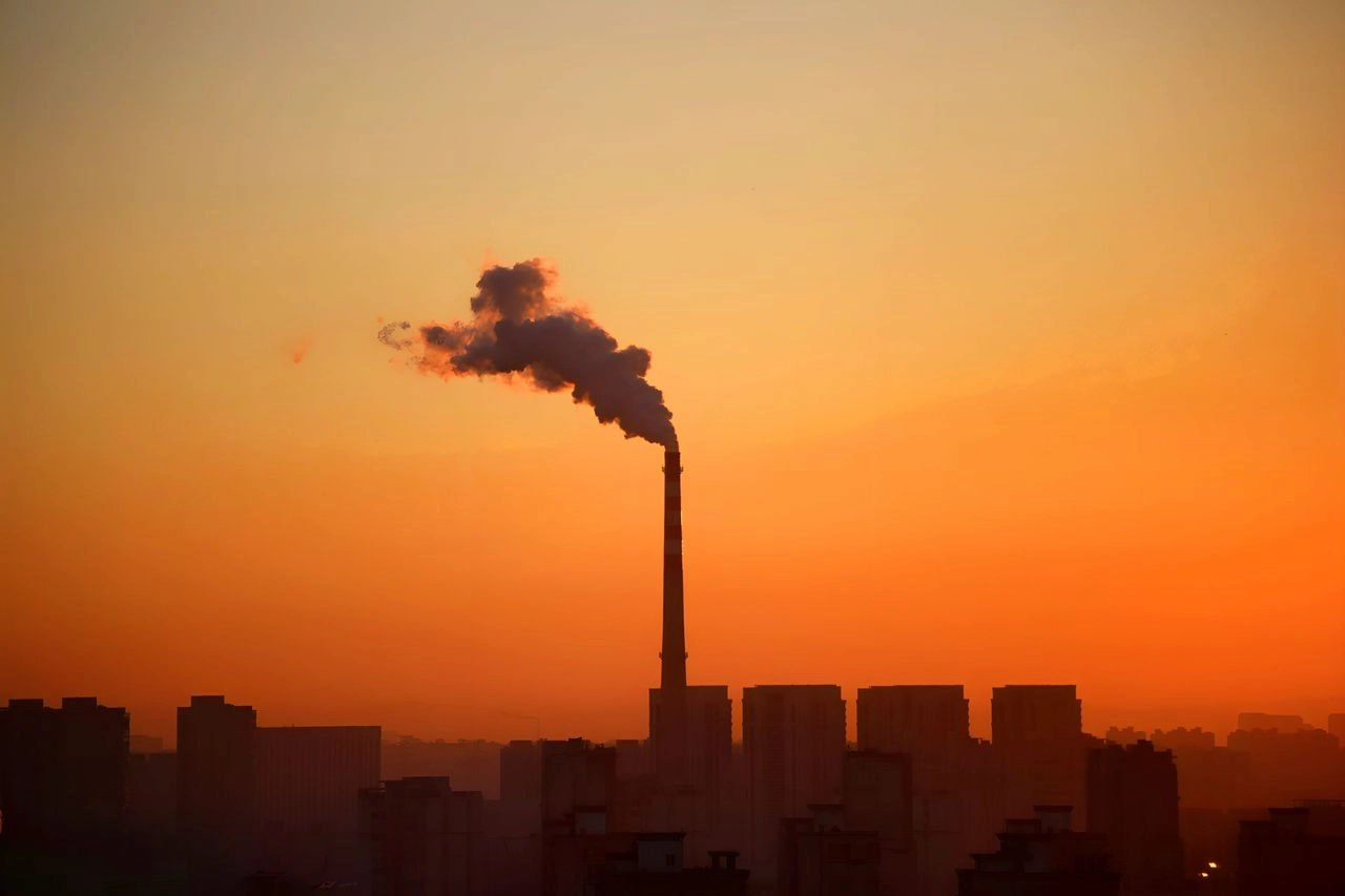 Una chimenea emite humo al amanecer sobre una ciudad la ONU asume que el mundo superará los 1,5 °C / Foto: UP