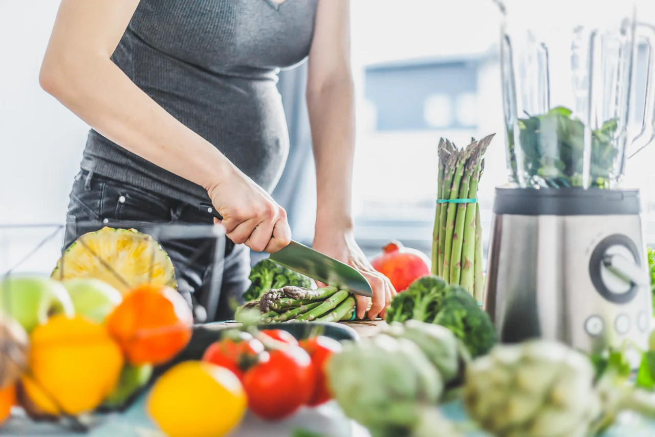 Una mujer embarazada corta espárragos entre frutas y verduras la dieta mediterránea en el embarazo se asocia con menos cólicos y eccema en el bebé / Foto: FP Una mujer embarazada corta espárragos entre frutas y verduras la dieta mediterránea en el embarazo se asocia con menos cólicos y eccema en el bebé / Foto: FP