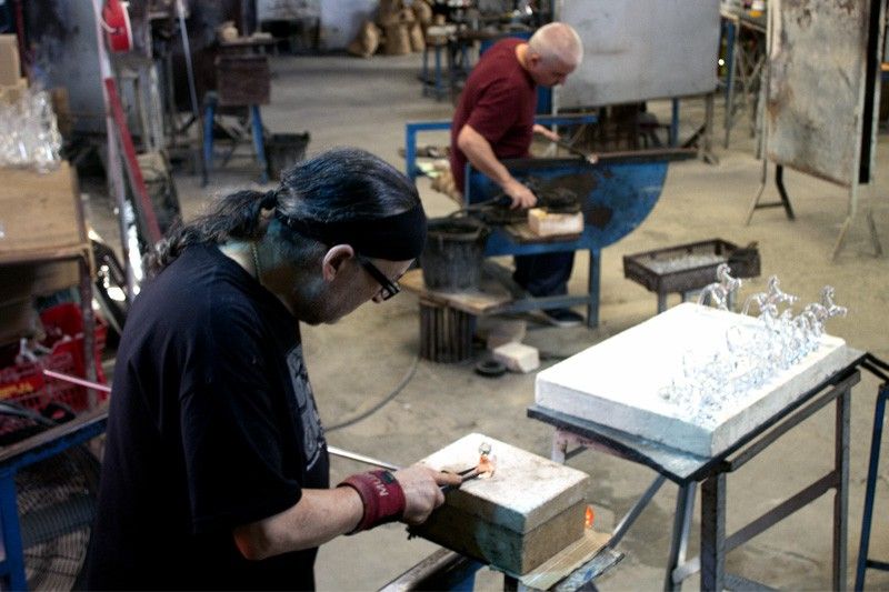 Dos trabajadores moldean el material en la vidriería San Juan, en el Poble Espanyol de Barcelona / Foto: CF