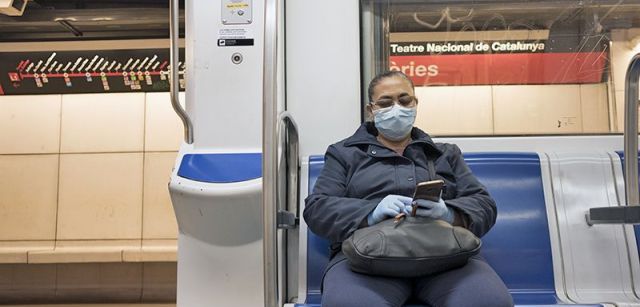 Una pasajera con máscara y guantes en un vagón semivacío del Metro de Barcelona / Foto: Josep Cano