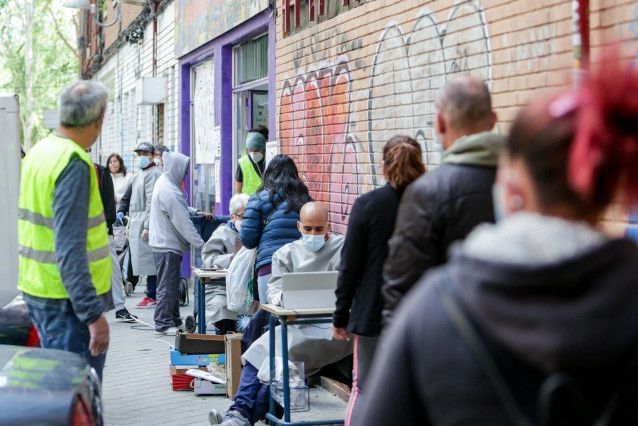 Cola de personas recogiendo bolsas de comida  y material de protección contra la COVID-19 en un comedor social del barrio madrileño de Aluche / Foto: EP