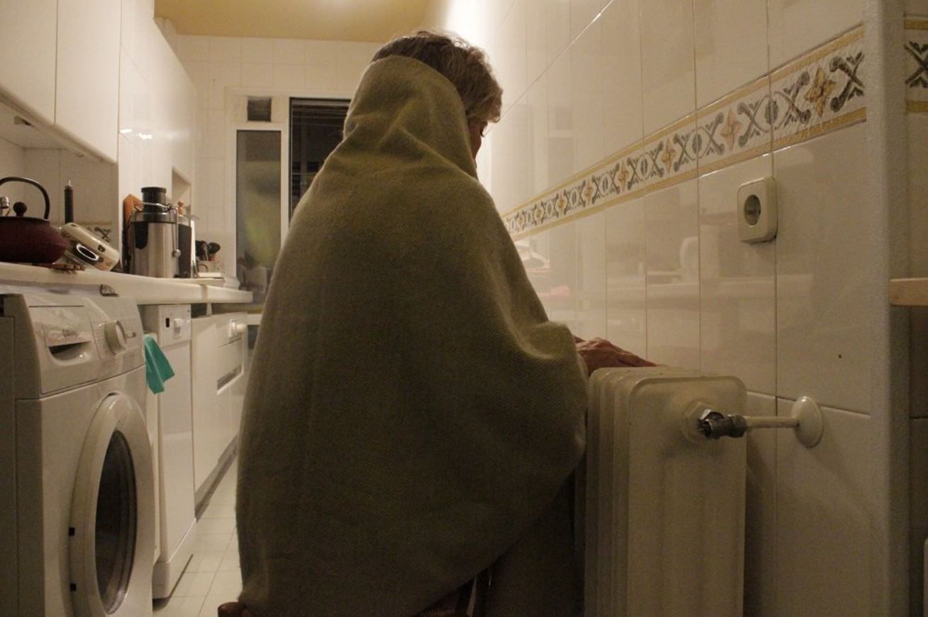 Una mujer se abriga con una manta en su domicilio ante la pobreza energética / Foto: Cruz Roja - EP