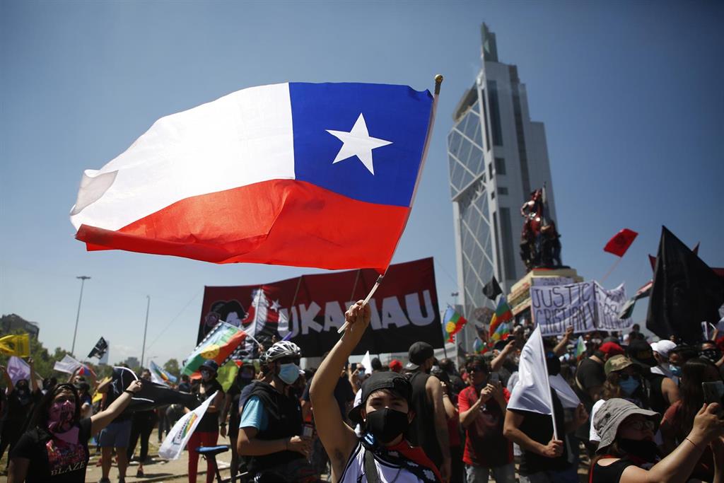 Un manifestante ondea la bandera de Chile durante las protestas por el primer aniversario del estallido social de octubre de 2019 / Foto: Marcelo Hernández - EP